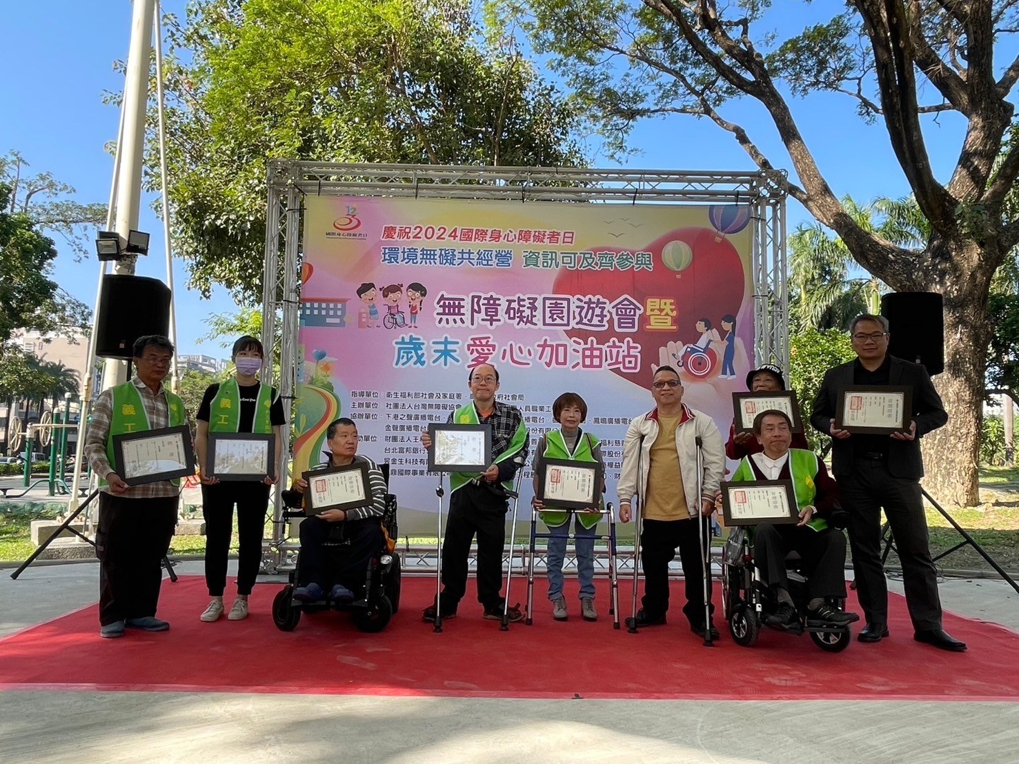 2024 無障礙園遊會暨歲末愛心加油站活動，與會者在活動背板前合影。