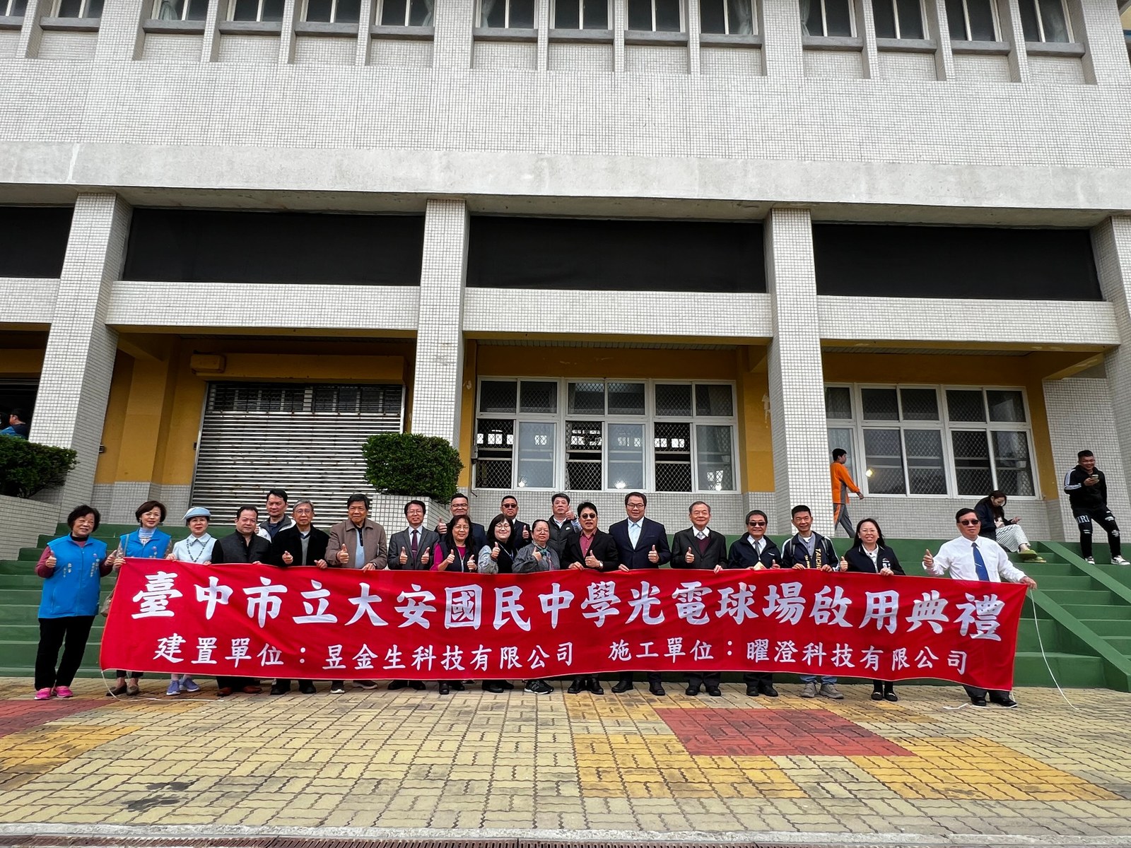 臺中市立大安國中光電球場啟用典禮合照，後方布條標示校名及昱金生建置單位。