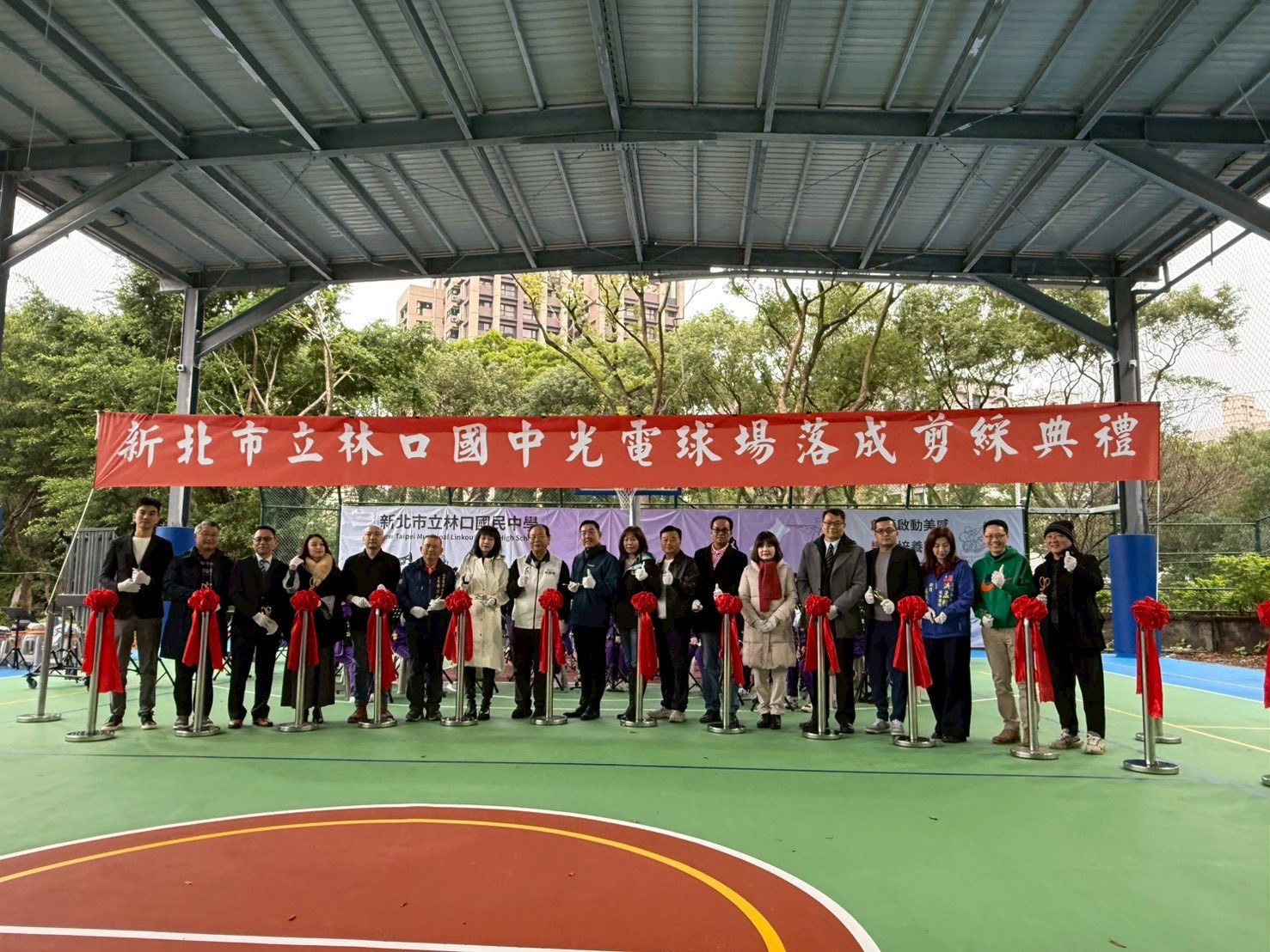 新北市立林口國中光電球場落成剪綵典禮，與會者在紅色典禮布條前合影。